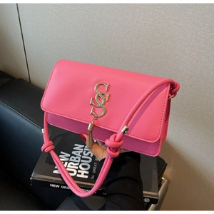 Close-up of neon pink leather crossbody bag with S-buckle tassel and knot strap detail