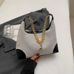 Dettaglio della borsa a tracolla in tela intrecciata con finiture in pelle nera e ciondolo cervo