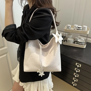 Large white woven tote bag with star pendant shown on model for casual spring style