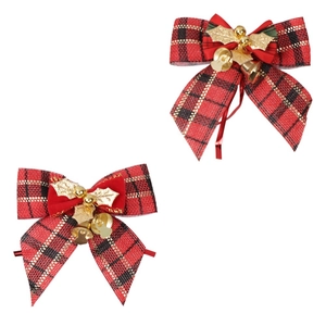Close-up of red plaid Christmas bows with golden bells and leaf ornaments