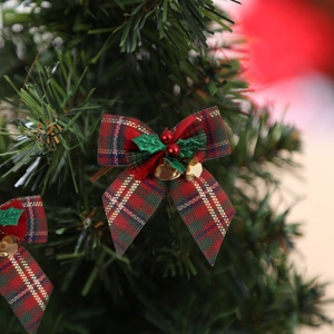 Close-up of plaid Christmas bow with holly leaves and bells on a green pine branch