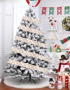 Gros plan du ruban en toile de jute à pois blancs sur une branche de sapin enneigé