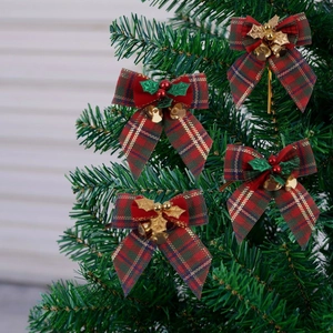 Detail of plaid Christmas bows with gold bells and holly berries on a tree branch