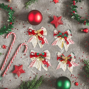 Close-up of four Christmas burlap bows with red truck print and metal bells on grey stone
