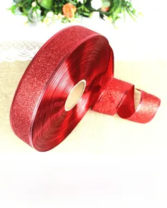Macro view of red glitter satin ribbon roll with metallic sheen and fine texture