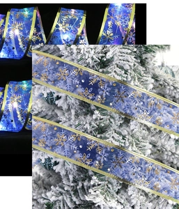 Close-up of blue LED Christmas ribbon with gold snowflake prints glowing on a tree