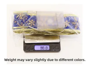 Detail shot of blue and gold LED snowflake ribbon on scale weighing 90.0g with battery box