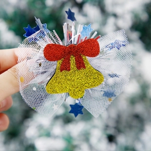 Close-up of a sparkling gold bell hair clip with red glitter bow and blue star sequins