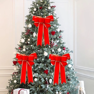 Velvet red Christmas bow with gold trim decoration hanging on a festive Christmas tree