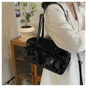 Dettaglio della borsa a tracolla nera plissettata con fiocco su un outfit blazer bianco