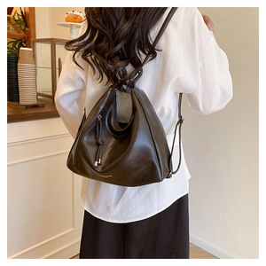 Detailed view of dark brown faux leather backpack with silver hardware on model