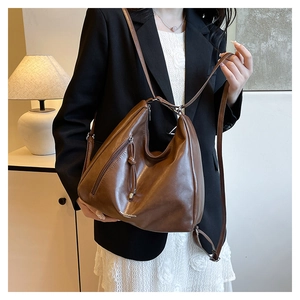 Détail macro du sac en cuir marron avec fermeture éclair à pompon et bandoulière réglable