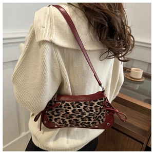 Detailed view of leopard print bag with red leather trim and ribbon bow details
