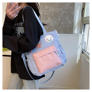 Detail of blue and pink contrast shoulder bag with large flap pocket and cute badges