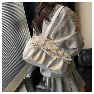 Dettaglio di una borsa tote in pelle beige lucida con eleganti tasche a fiocco pieghettate