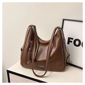 Détail du sac cabas en cuir marron foncé avec inscription FASHION & BAGS et pompon