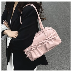 Elegante borsa a spalla rosa con pieghe e fiocchi indossata da modella in blazer nero