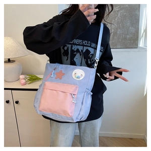 Detail der Nylon-Umhängetasche im Color-Block-Design mit Stern-Patch und rosa Fronttasche