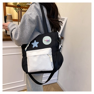 Detail of black and white canvas tote bag with star patch and beaded charm on shoulder strap
