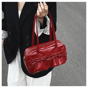 Borsa a spalla rossa lucida con dettagli a fiocco indossata su un blazer nero