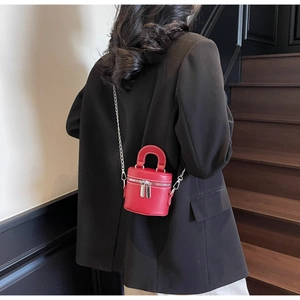 Detail einer roten Mini-Beuteltasche mit Rundgriff und Silberkette auf schwarzem Blazer