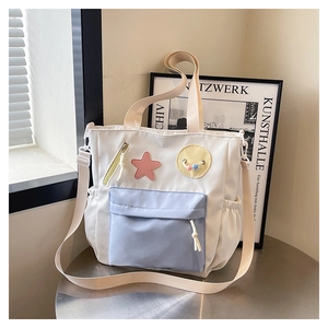 Detailed shot of white tote bag with light blue zipper pocket and cartoon star patches