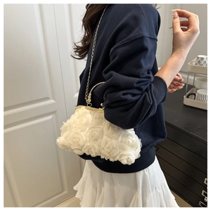 Detail of a white 3D rose textured handbag with gold handles and chain strap