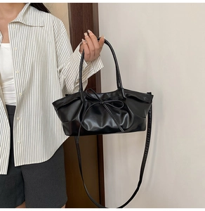 Detail of black leather dumpling bag featuring elegant drawstring bow and pleated texture