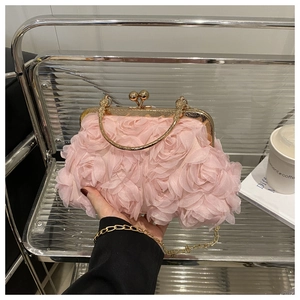 Detail view of 3D pink fabric roses and gold metal frame on an elegant shell clutch bag