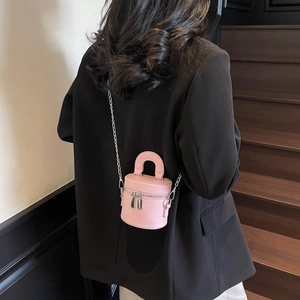 Rosa Zylindertasche aus Leder mit Handgriff und silbernem Kettenriemen am Modell