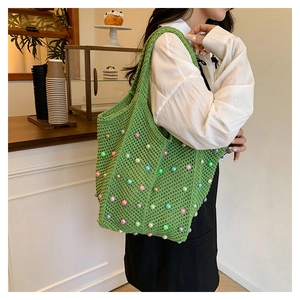 Detail of green crochet tote bag with colorful faux pearls and handmade texture