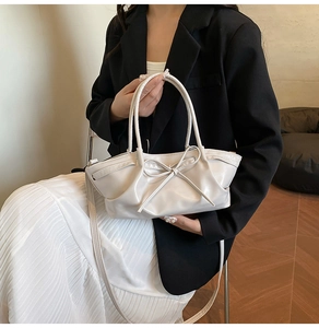 Detail of off-white dumpling bag with pleated texture and stylish bow decoration