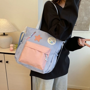 Blue canvas tote bag with pink star patch and adjustable strap shown on model