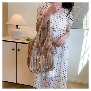 Detail of hand-woven tote bag with colorful pearls and soft knit texture on a shoulder strap