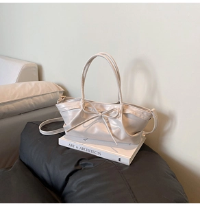 Detail of cream dumpling bag with bow decoration and pleated design on an art book