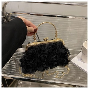 Close-up of black floral evening bag with 3D fabric roses and golden ring handle