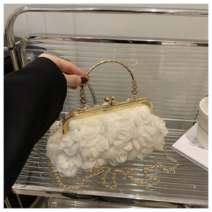 Detail of elegant white floral evening bag featuring chiffon petals and a golden metal handle
