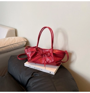 Detail of red glossy leather dumpling bag with pleats and a delicate ribbon bow accent