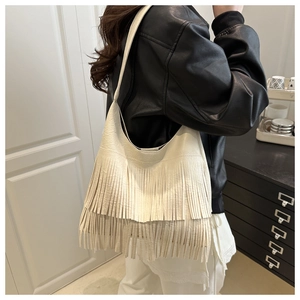 Detailed view of bohemian beige tote bag featuring layered long tassels and faux leather texture