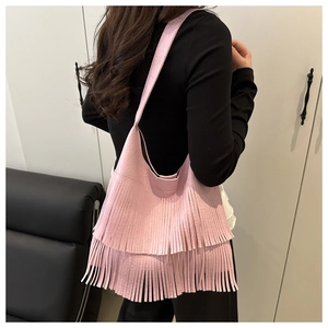 Dettaglio della borsa a tracolla rosa con lunghe nappe bohémien indossata da una modella