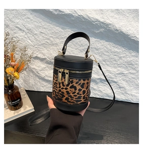 Close-up of leopard print bucket bag featuring gold double zippers and black strap