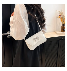 Detailed back view of a white flap crossbody bag with silver bow buckle on model