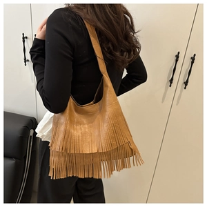 Detail view of brown faux leather tote bag featuring two layers of dense bohemian fringe