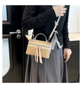 Gros plan sur un sac à main tissé kaki avec doubles fermetures éclair et longs pompons