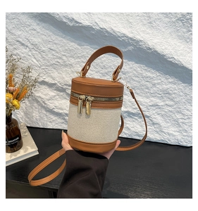 Detail of canvas and brown leather bucket bag with gold hardware and shoulder strap
