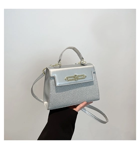 Detail of silver crossbody bag featuring glitter fabric and elegant metal turn-lock