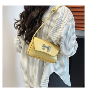 Close-up of stylish yellow PU leather bag with elegant silver metal bow detail
