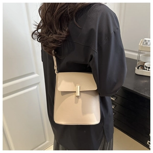 Détail du sac bandoulière crème avec fermoir métallique doré et texture cuir élégante