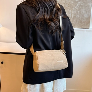 Minimalist beige crossbody bag with DUONING logo shown on person in indoor setting