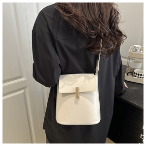 Gros plan du sac carré crème avec fermoir doré sur une chemise noire élégante